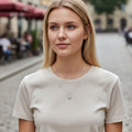 BlingbyAnvika 925 silver necklace with oval iridescent pendant and two circle accents on a woman wearing a beige t-shirt.