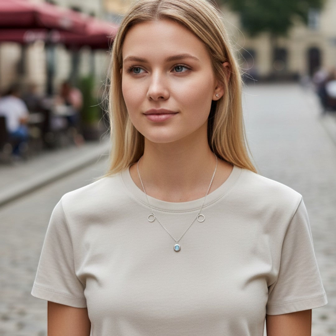 BlingbyAnvika 925 silver necklace with oval iridescent pendant and two circle accents on a woman wearing a beige t-shirt.