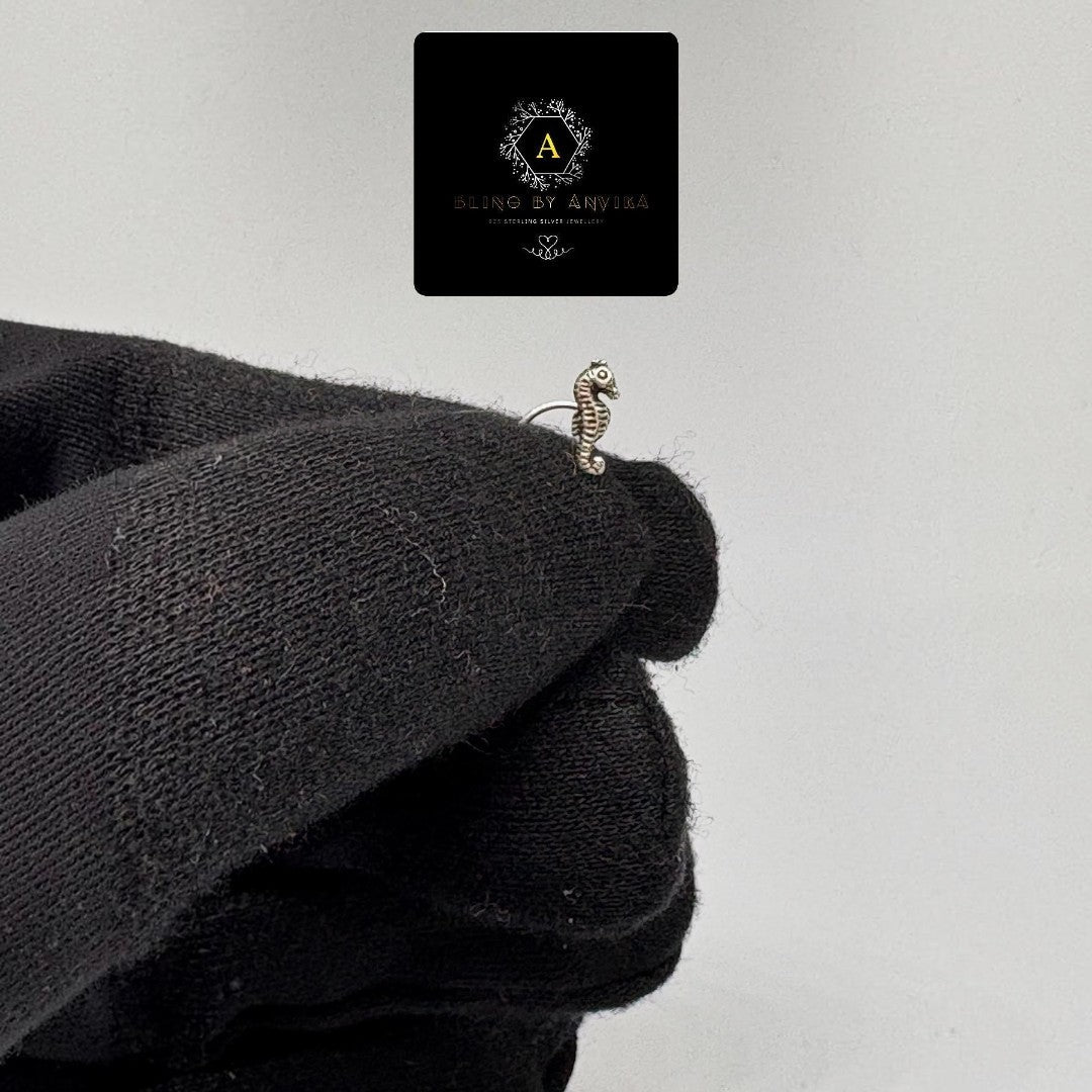 BlingbyAnvika 925 sterling silver seahorse nose pin with intricate detailing held by a gloved hand