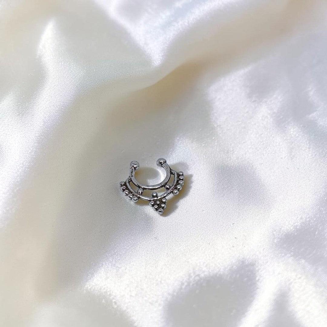 BlingbyAnvika 925 sterling silver septum ring with ornate tribal-inspired bead detailing on a white satin background.