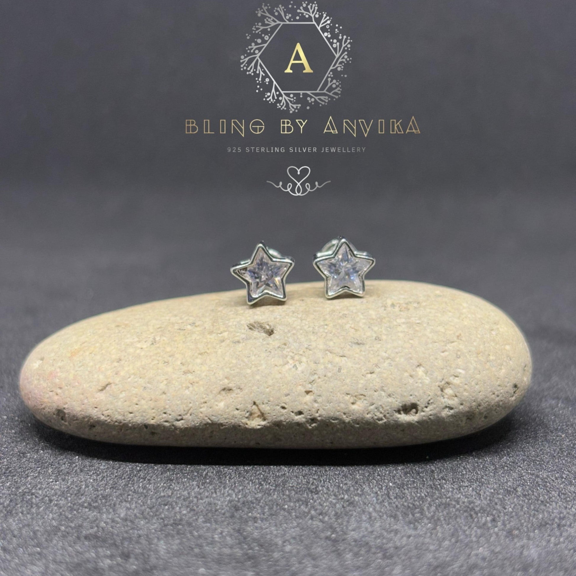 BlingbyAnvika sterling silver star stud earrings with sparkling AAA-grade zircon stones on a natural stone surface.