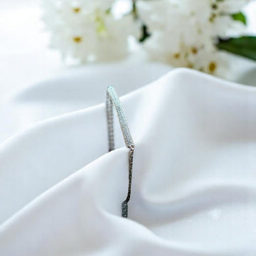 BlingbyAnvika 925 sterling silver bracelet with small clear stones on a bar, set against white satin.