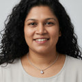 BlingbyAnvika 925 sterling silver single stone necklace worn by a woman with curly hair against a grey background
