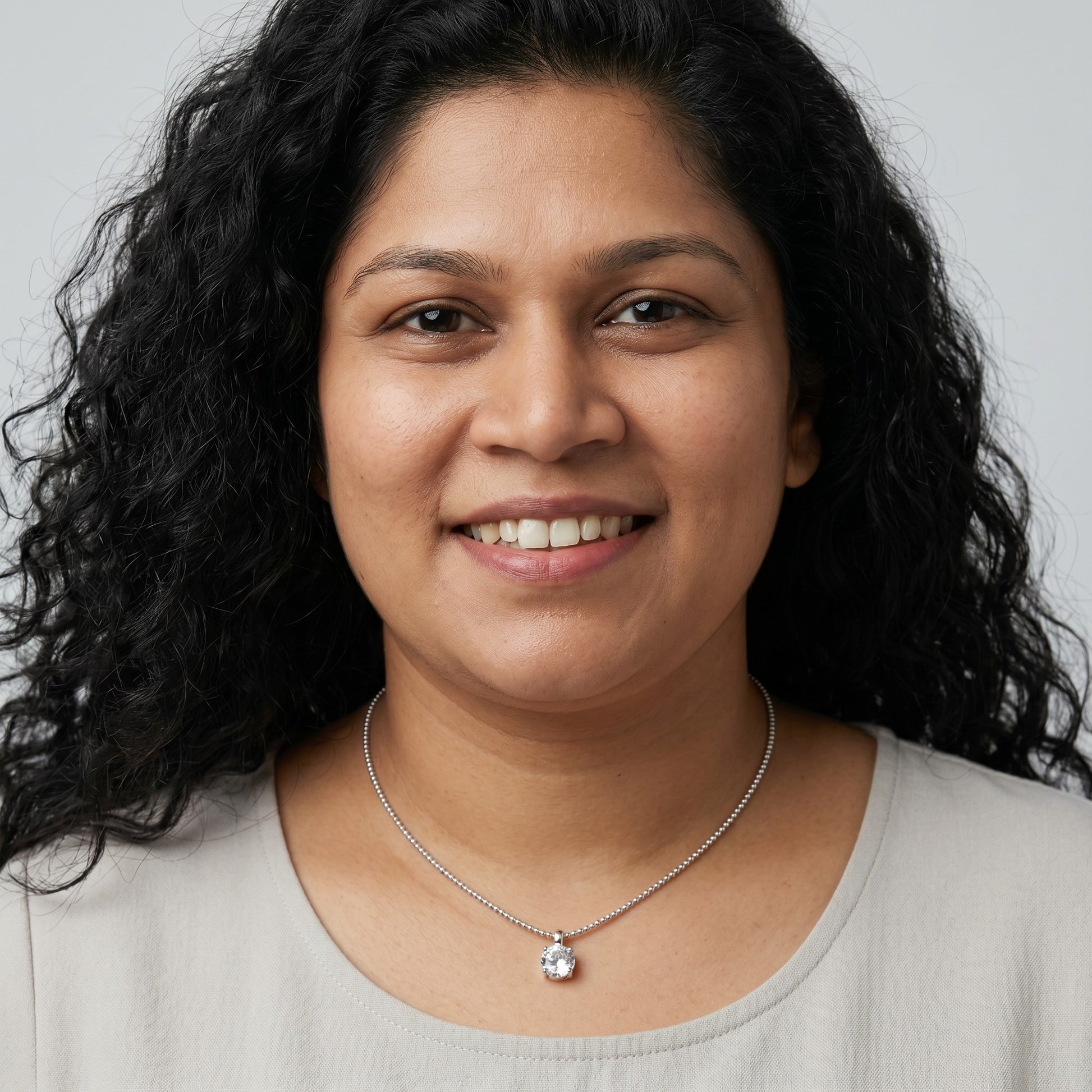 BlingbyAnvika 925 sterling silver single stone necklace worn by a woman with curly hair against a grey background