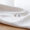 BlingbyAnvika sterling silver heart-shaped stud earrings featuring sparkling AAA-grade zircon stones on white fabric.