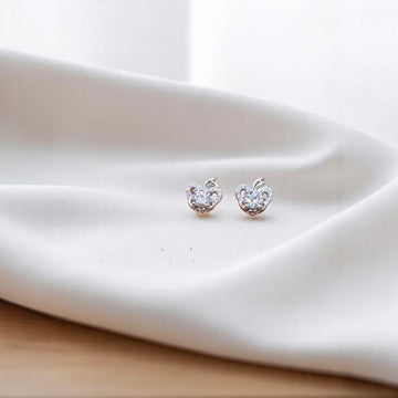BlingbyAnvika sterling silver heart-shaped stud earrings featuring sparkling AAA-grade zircon stones on white fabric.