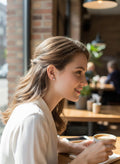 BlingbyAnvika sterling silver star-shaped zircon stud earrings worn by a smiling woman in a cafe