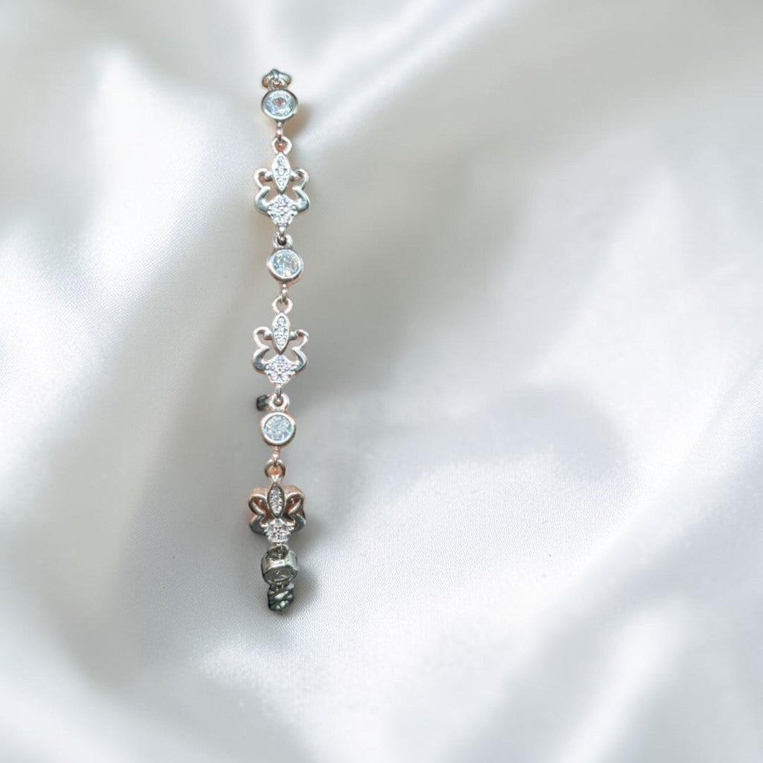 BlingbyAnvika sterling silver bolo bracelet with cubic zirconia and fleur-de-lis charms. Adjustable clasp.