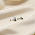 BlingbyAnvika 925 sterling silver stud earrings with vibrant green stones on a soft beige fabric background.