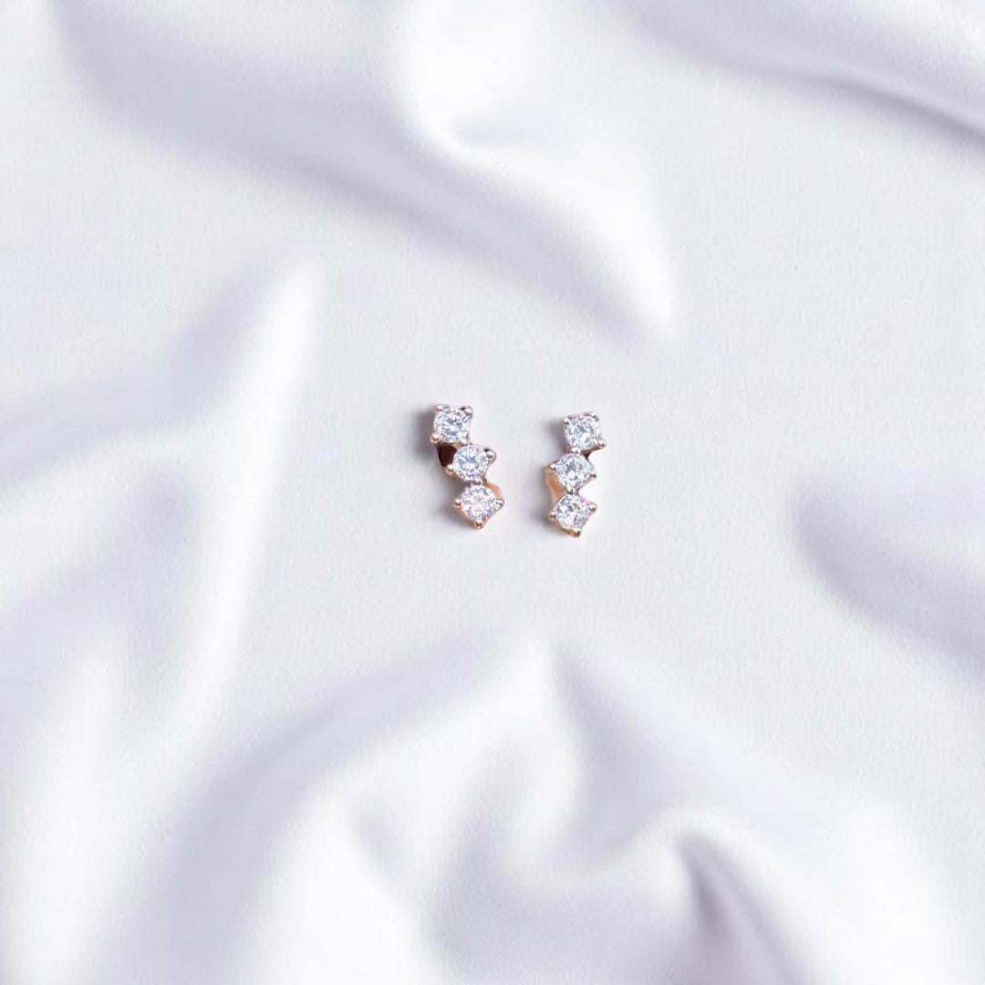 BlingbyAnvika sterling silver stud earrings featuring three sparkling AAA-grade zircon stones on white fabric.